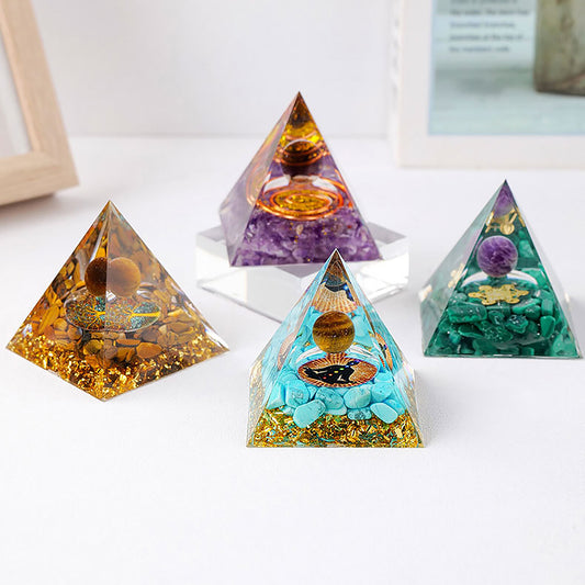 A set of four decorative pyramids, each uniquely filled with a mix of gemstones, metallic elements, and symbolic designs, creating a vibrant, eye-catching display. Each pyramid features a central sphere and intricate layering of colors like amber, purple, turquoise, and green. Positioned on a light surface, these pieces exude a mystical, meditative ambiance suitable for decorative or spiritual purposes.